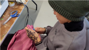 Een vrouw werkt aan een roze stof met een tornmesje