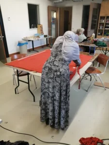 Een vrouw knipt een rood stuk stof in het naaiatelier.
